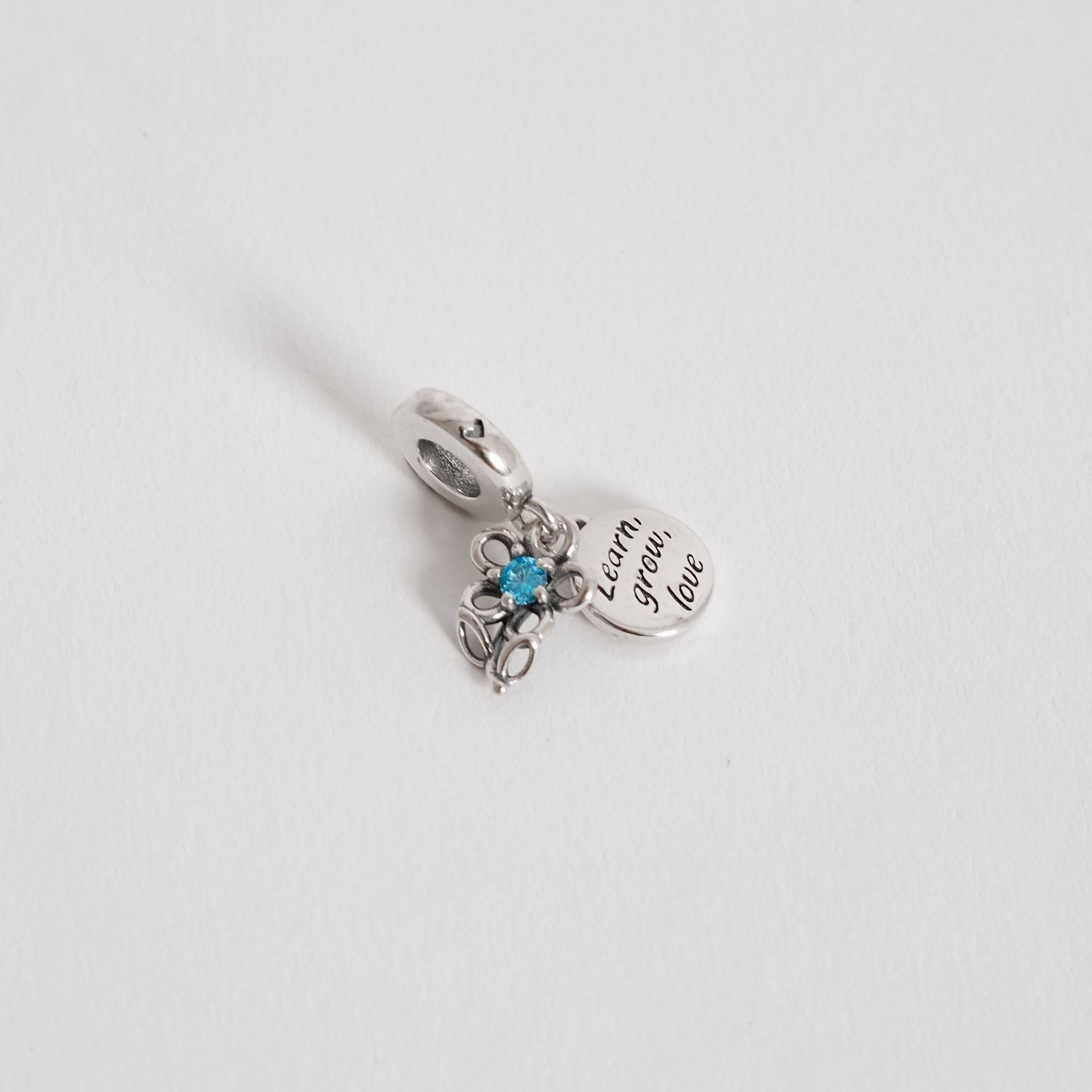 Berloque pingentes flor com zircônia azul e placa learn, grow, love envelhecido