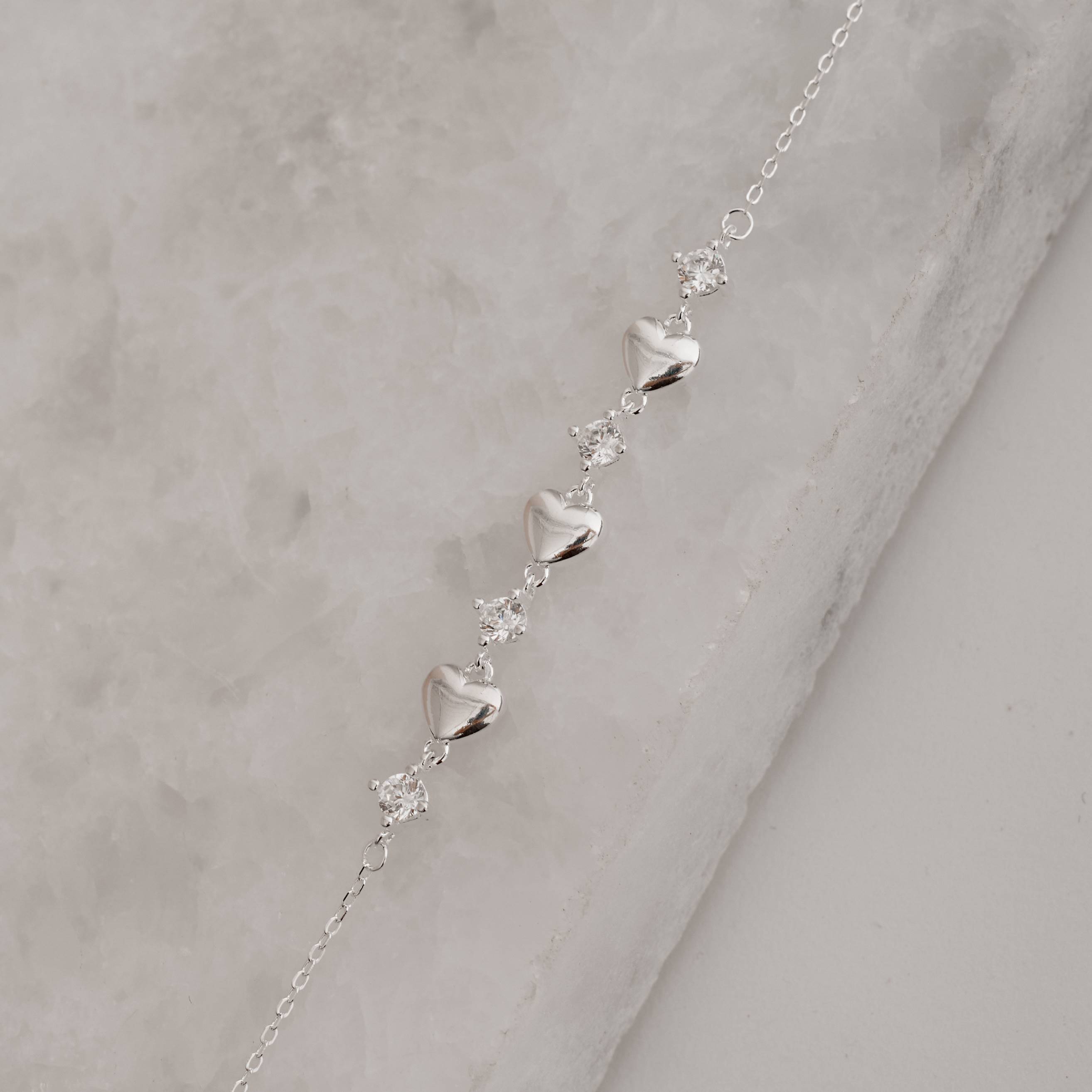 Imagem Secundária Pulseira entremeios zircônias e corações 16+4cm